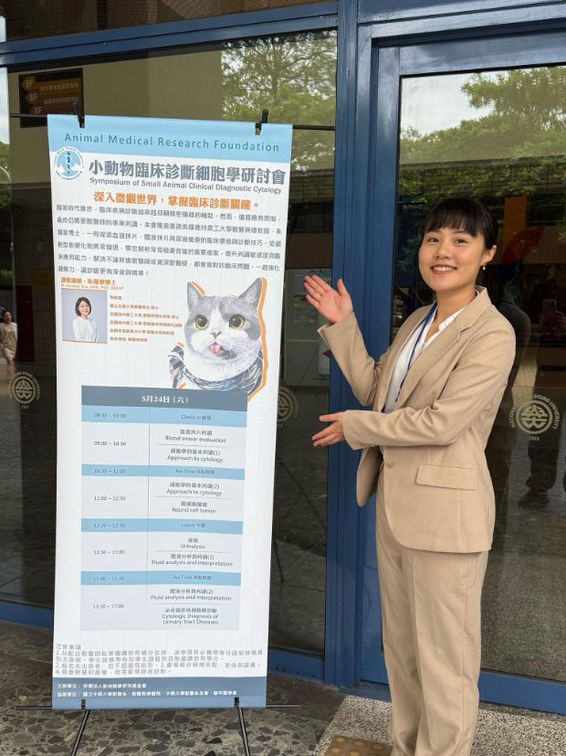 Dr. Chu beside the programme banner for the Symposium of Small Animal Clinical Diagnostic Cytology